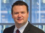 A business executive in a suit posing for a portrait in a modern office setting.